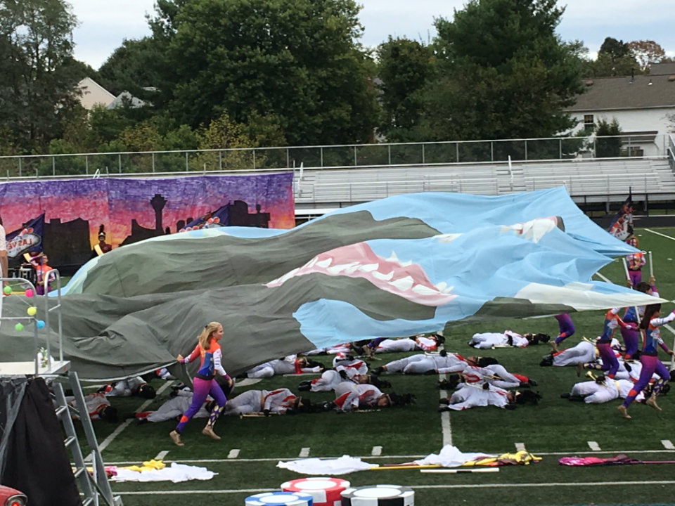 Photo of Godzilla flyover flag as it is spread out over the band. Photo of Godzilla flyover flag as it is spread out over the collapsing marching band members dressed as Elvis.
